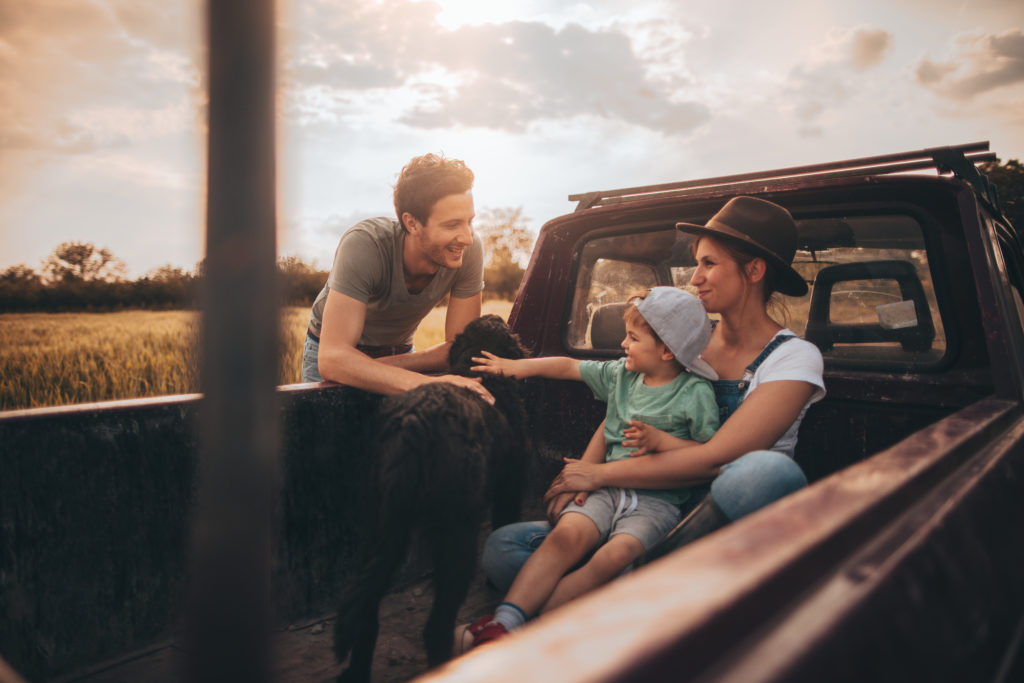Photo of young family while visiting family farm in their pick-up truck.